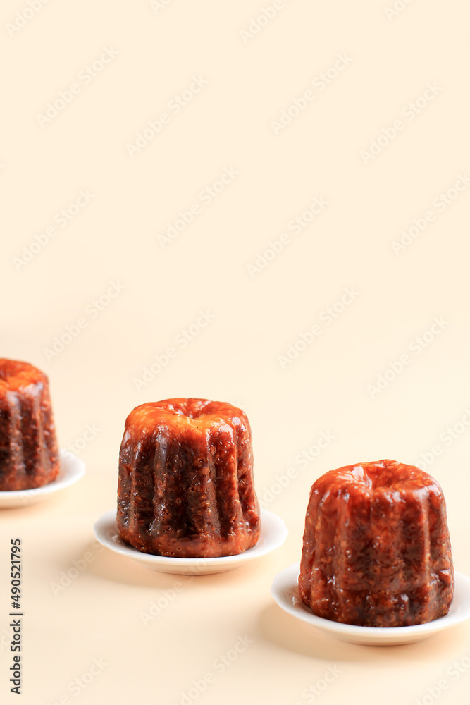 Caneles Cake, French Sweet Dessert on Clean Cream Background