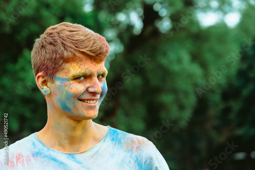 portrait of young happy man dirt in holi paints