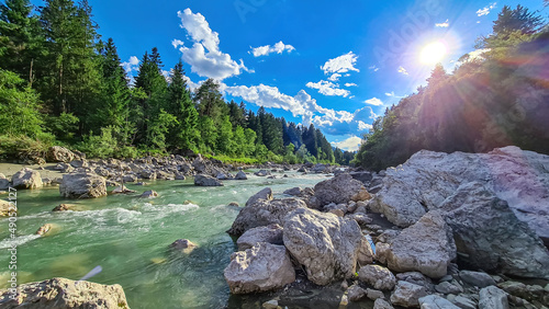 River Gail flowing through the Schuett in the natural park Dobratsch in Villach, Carinthia, Austria. Gailtaler and Villacher Alps. Riverbank is full of massive rocks. Swimming in crystal clear water photo