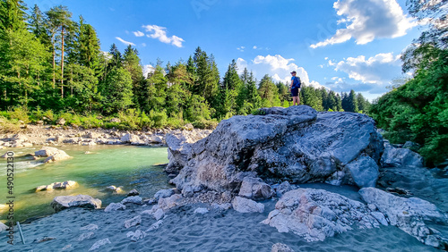 Man standing on rock with scenic view on river Gail flowing through the Schuett in natural park Dobratsch in Villach, Carinthia, Austria. Gailtaler and Villacher Alps. Crystal clear water. Freedom photo