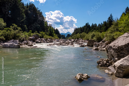 River Gail flowing through the Schuett in the natural park Dobratsch in Villach, Carinthia, Austria. Gailtaler and Villacher Alps. Riverbank is full of massive rocks. Swimming in crystal clear water photo