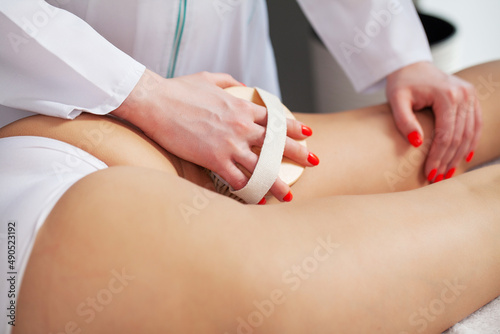 Woman making anti cellulite or lymphatic thigh massage at home