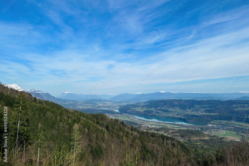 Scenic view on the Drava river in the Rosental valley on the way to Sinacher Gupf in Carinthia, Austria. Forest in early spring. The Hohe Tauern mountain range can be seen in the back. Sunny day. Hike Scenic view on the Drava river in the Rosental valley on the way to Sinacher Gupf in Carinthia, Austria. Forest in early spring. The Hohe Tauern mountain range can be seen in the back. Sunny day. Hike