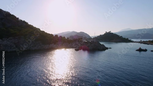 Flyover a scenic view with a sailboat in harsh lighting at Kas Kekova area Aerial low angle shot