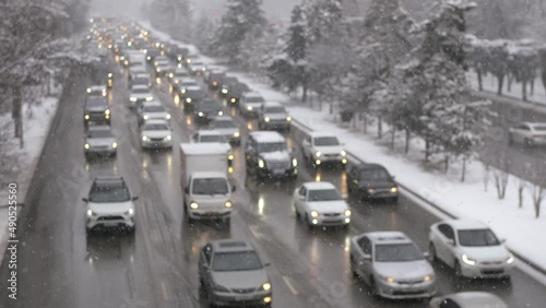 Traffic jam with a lot of cars on a city street during a snowfall on a winter day.
