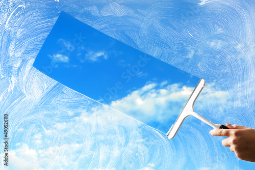 Washing of window with detergent and squeegee against blue sky photo