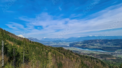 Scenic view on the Drava river in the Rosental valley on the way to Sinacher Gupf in Carinthia, Austria. Forest in early spring. The Hohe Tauern mountain range can be seen in the back. Sunny day. Hike