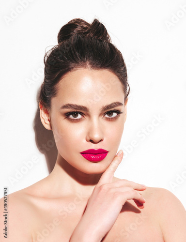 Fashion beauty portrait of young brunette woman with evening stylish makeup and perfect clean skin. Sexy model with hair in a bun posing in studio. With pink bright natural lips. Isolated on white