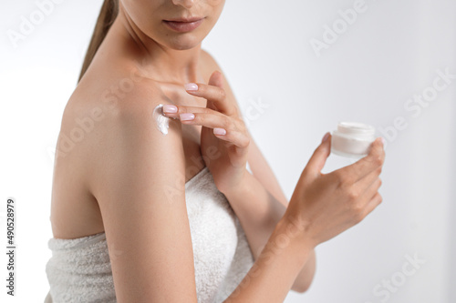 Close up of woman applying body lotion on bare shoulders