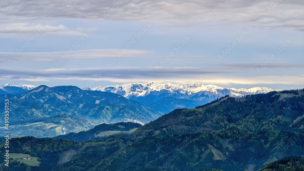 Panoramic view on the Eisenerzer Alps from below mount Roethelstein near Mixnitz in Styria, Austria. Snow capped mountain of the Ennstal Alps beyond the Grazer Bergland in Styria, Austria. Hochtor