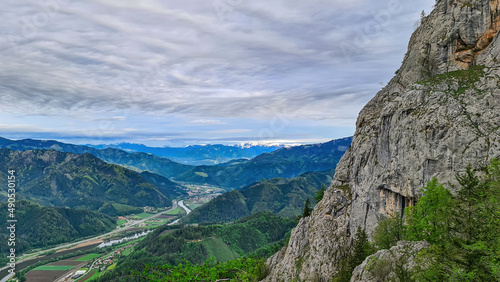 A rock formation with scenic view from mount Roethelstein near Mixnitz in Styria, Austria. Landscape of green alpine meadow and a small village in the valley of Grazer Bergland in Styria, Austria photo