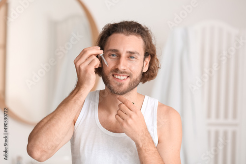 Young man using serum for s...