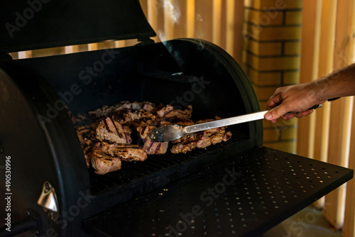 Juicy cuts of beef and pork meat on an open grill. Summer vacation barbecue with friends. Soft selective focus.