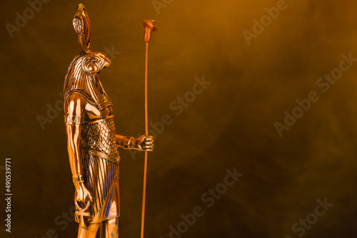 metal golden statue of the Egyptian sun god Ra on a black background with smoke