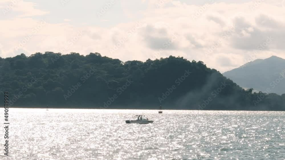 Small fishing boat navegating over the Panama Canal Waters in a cloudy warm morning from Panama City's Causeway of Amador, green leafy forest land in Panama's summer time Small fishing boat navegating over the Panama Canal Waters in a cloudy warm morning from Panama City's Causeway of Amador, green leafy forest land in Panama's summer time