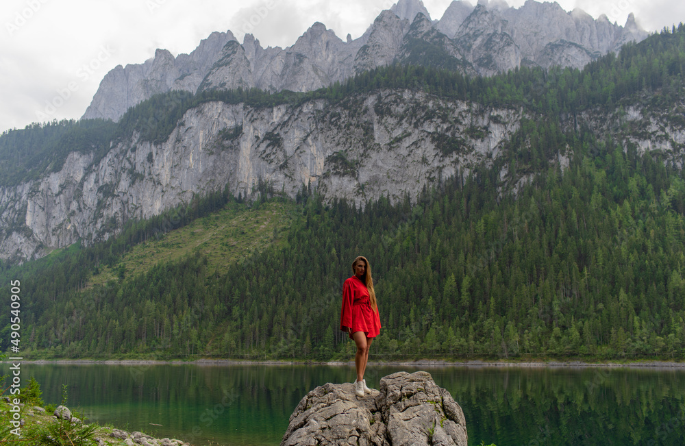 Beautiful girl in a red dress in the mountains near the lake