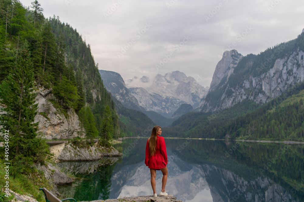Naklejka premium Beautiful girl in a red dress in the mountains near the lake