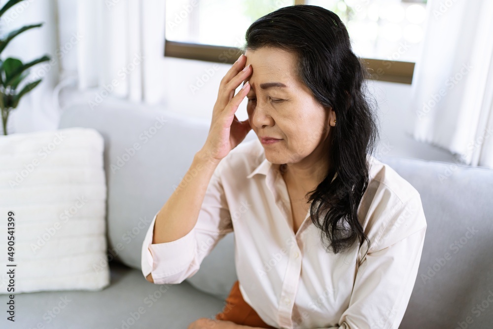 Middle age Asian woman touching forehead having headache suffering from. migraine feeling sick or depression Middle age Asian woman touching forehead having headache suffering from. migraine feeling sick or depression