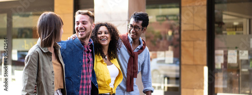 Horizontal banner or header with multi-cultural friends walking in city center - Happy guys and girls having fun around shopping town streets - University students on travel vacations