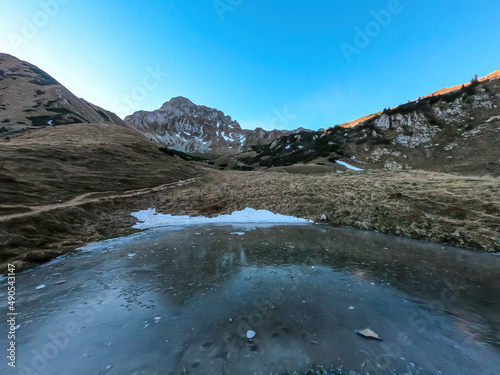 Frozen Krumpensee with a panoramic view on mount Eisenerzer Reichenstein in Styria, Austria, Europe. Austrian Alps. Ennstal Alps. The valley is in the shadows, sunrise. Hiking trail, Wanderlust. photo