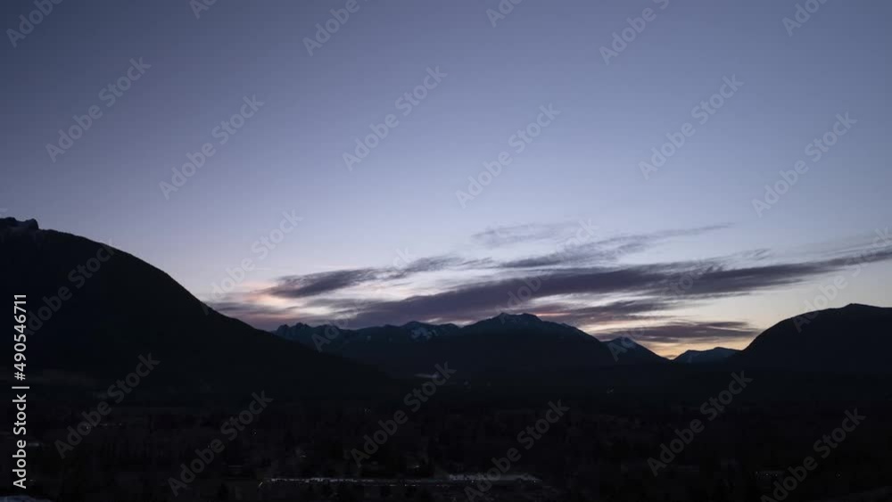 Clouds move across a dark early morning sky, mountains silhouetted, morning glow, aerial hyper lapse Clouds move across a dark early morning sky, mountains silhouetted, morning glow, aerial hyper lapse