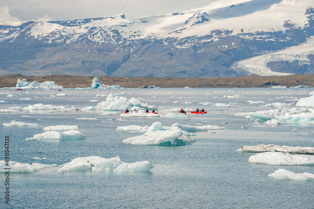 Panoramic view of Glacier Lagoon Jokulsarlon with icebergs and Vatnajokull Glacier tongue, Iceland, summer, with a touristic kayaking and people.