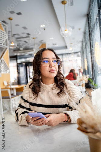 Young beautiful woman works through her smartphone in a cafe  freelancer