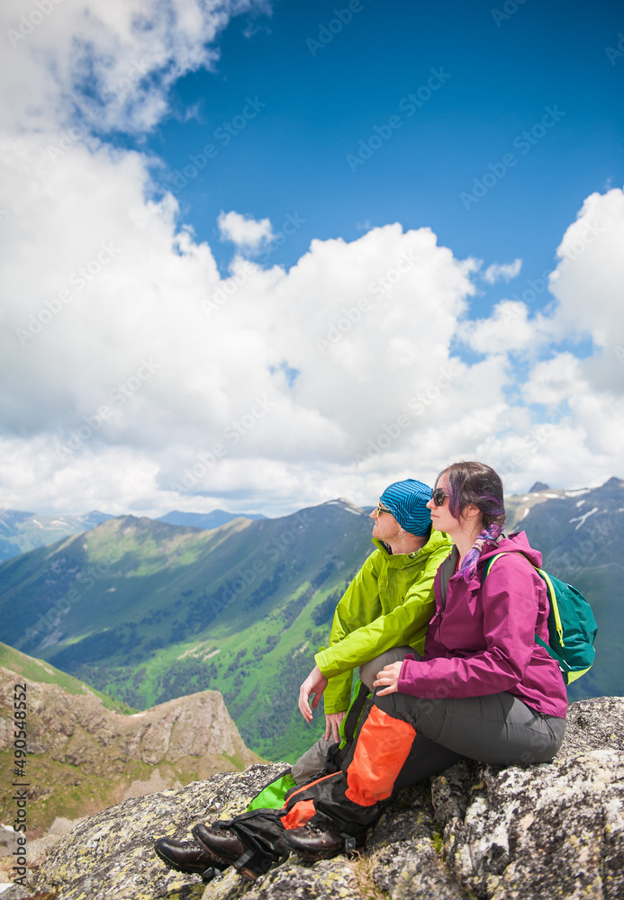 Brave couple woman and man hiker sitting on the top of mountain