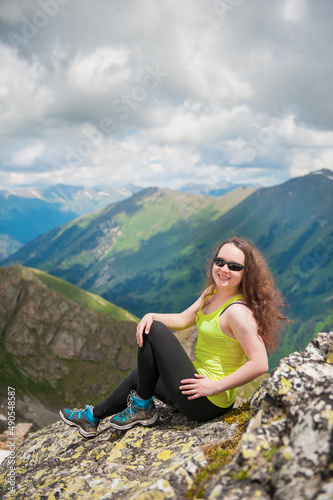 Beautiful Woman hiker sitting on the top of mountain