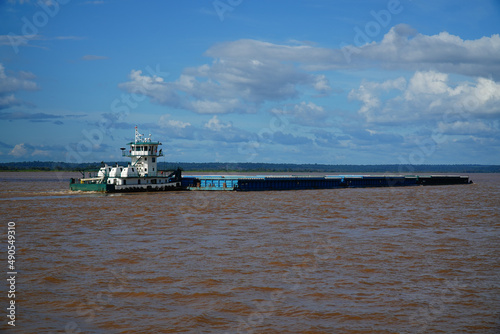 A tugboat pushes a large barge upstream on the Amazon river, Pará state, Brazil.