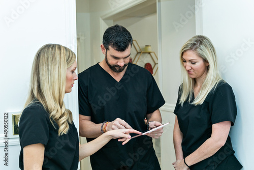 Konstfotografi A male physician doctor at a medical spa and wellness clinic speaking to two fem