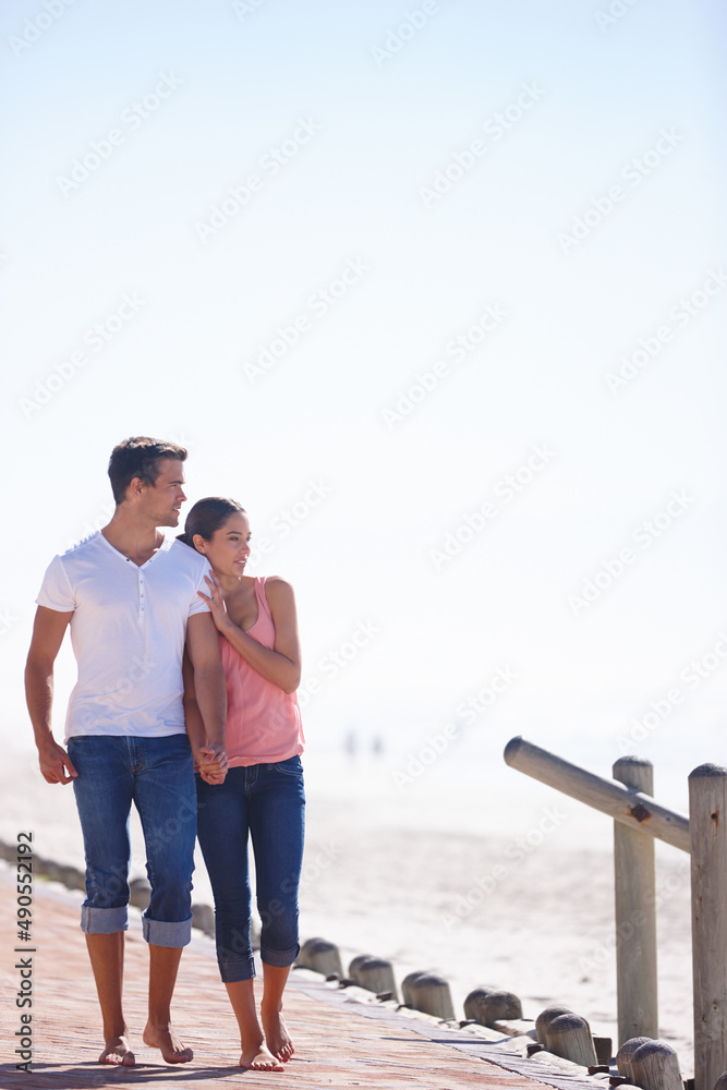 Love and a beautiful view. Full length shot of an attractive young couple walking beside the sea. Love and a beautiful view. Full length shot of an attractive young couple walking beside the sea.