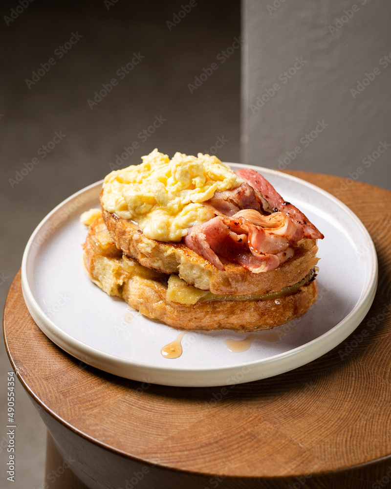 Toast with fried bananas, bacon, scrambled eggs and maple syrup