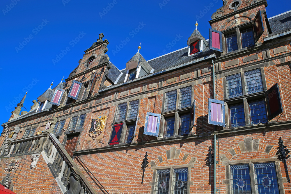Low angle view on medieval renaissance red brick style facade against cloudless blue sky