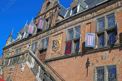 Low angle view on medieval renaissance red brick style facade against cloudless blue sky  photo