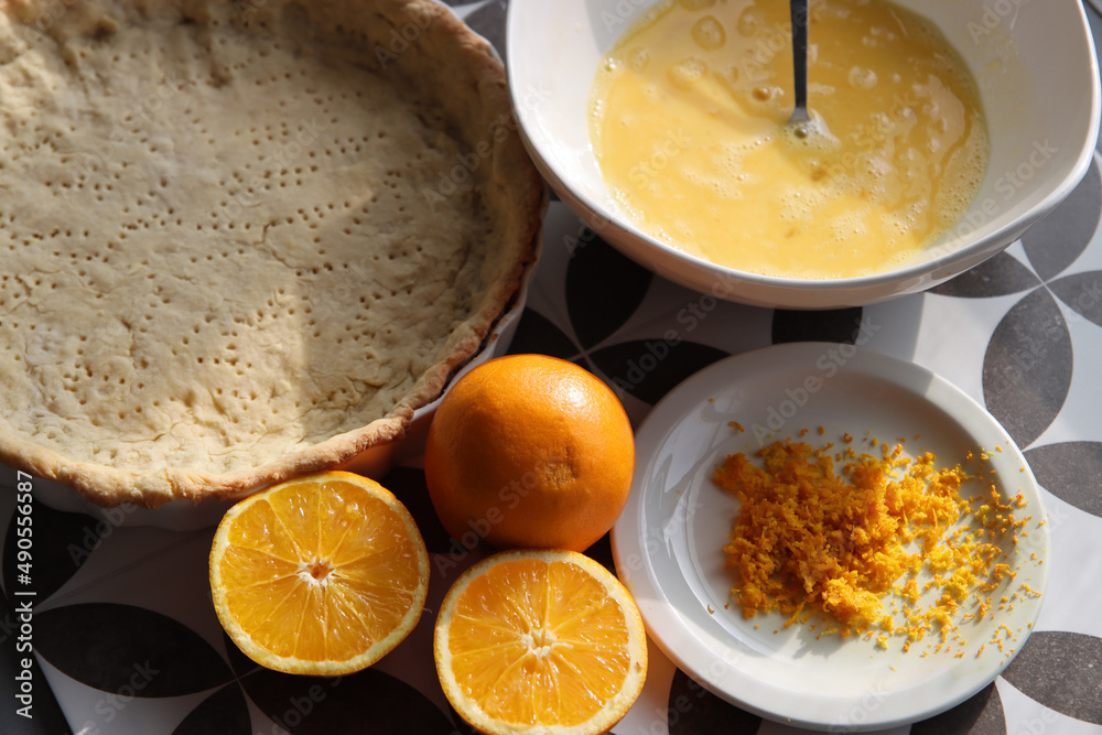 Making orange pie. Close up photo of fresh ingredients. Crusty dough, oranges, sugar, eggs top view photo. 