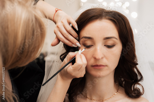 Girl makeup artist brush to apply eye shadow on the eyelid of the model. Close-up