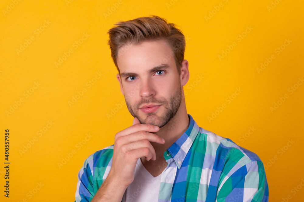 Handsome unshaven man portrait stroking chin with serious look yellow background, face Handsome unshaven man portrait stroking chin with serious look yellow background, face