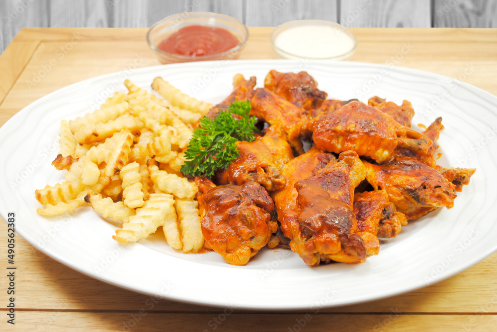 A Platter of French Fries Served and Spicy baked Buffalo Wings A Platter of French Fries Served and Spicy baked Buffalo Wings