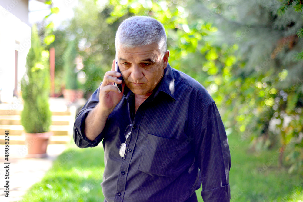 older man talking on cellphone close up, grandfather chatting with relatives or grandchildren, mature male making or answering phone call, having pleasant conversation. older man talking on cellphone close up, grandfather chatting with relatives or grandchildren, mature male making or answering phone call, having pleasant conversation.