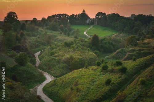 Beautiful evening landscape. The road between green hills at sunset.