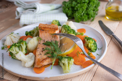 Healthy fish dish with fried salmon fillet and imperial vegetables on a plate with dill
