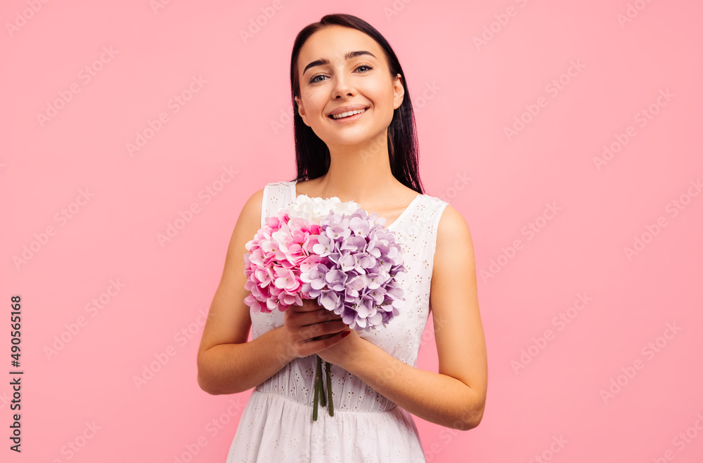 woman with a flower bouquet with peony flowers in her hands. Woman on a pink background, celebrating mother's day woman with a flower bouquet with peony flowers in her hands. Woman on a pink background, celebrating mother's day