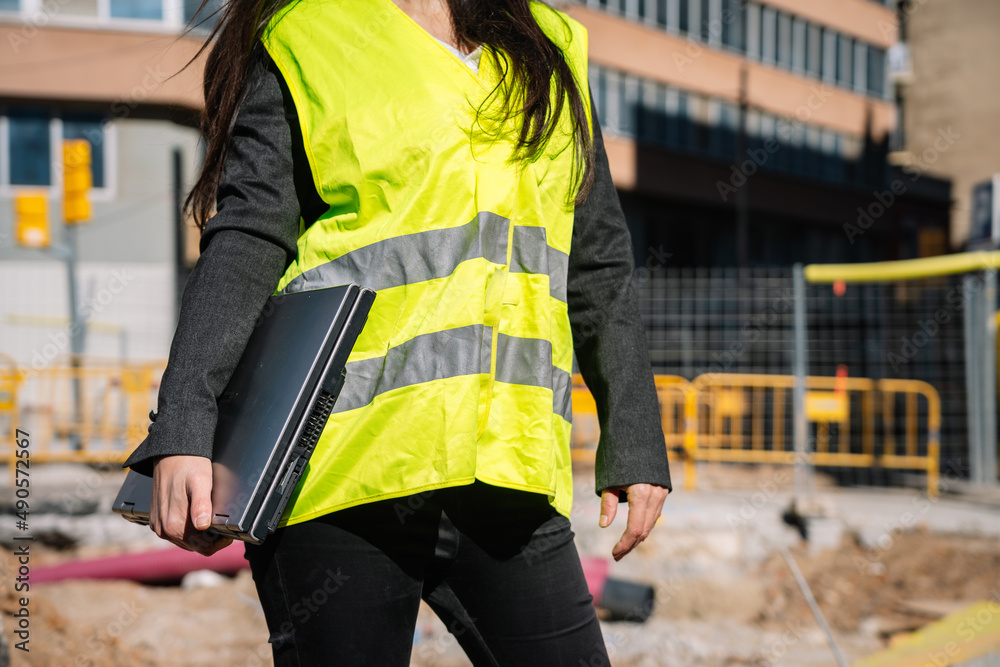 Crop faceless female inspector with netbook standing at construction site Crop faceless female inspector with netbook standing at construction site