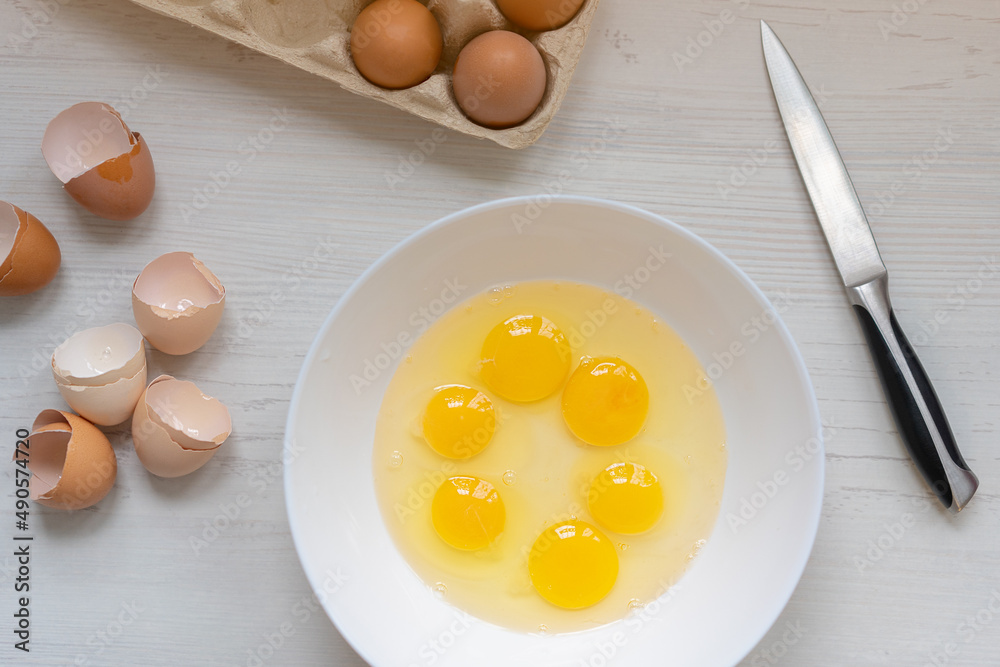 cooking process, eggs in a white bowl on the kitchen table, flat view, breakfast concept cooking process, eggs in a white bowl on the kitchen table, flat view, breakfast concept