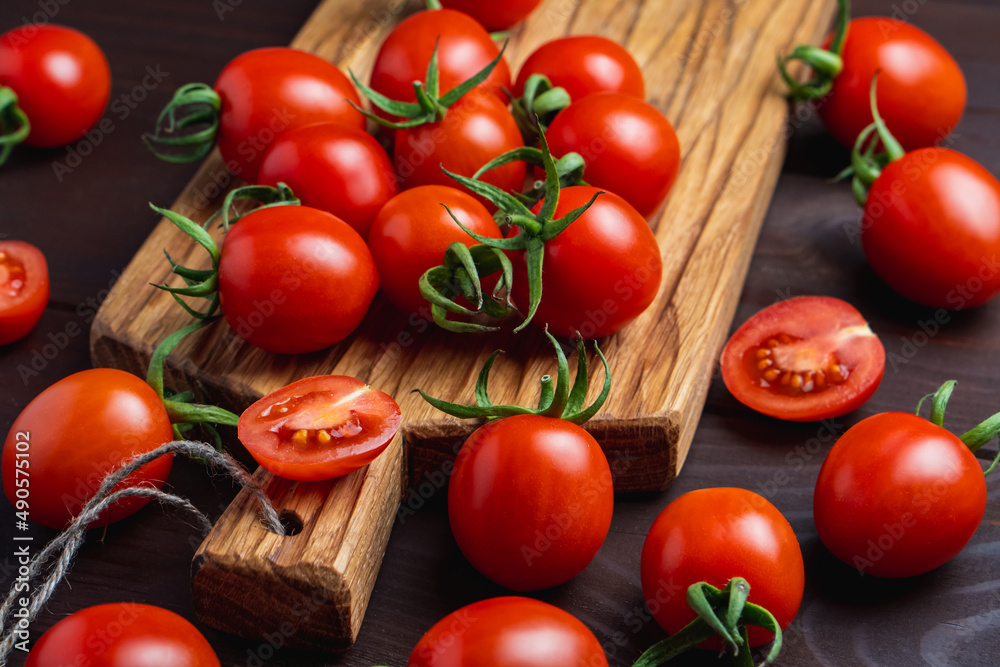 Red tomato in glass bowl on cutting board on wooden table. Organic healthy food. Cooking Ingredients Red tomato in glass bowl on cutting board on wooden table. Organic healthy food. Cooking Ingredients