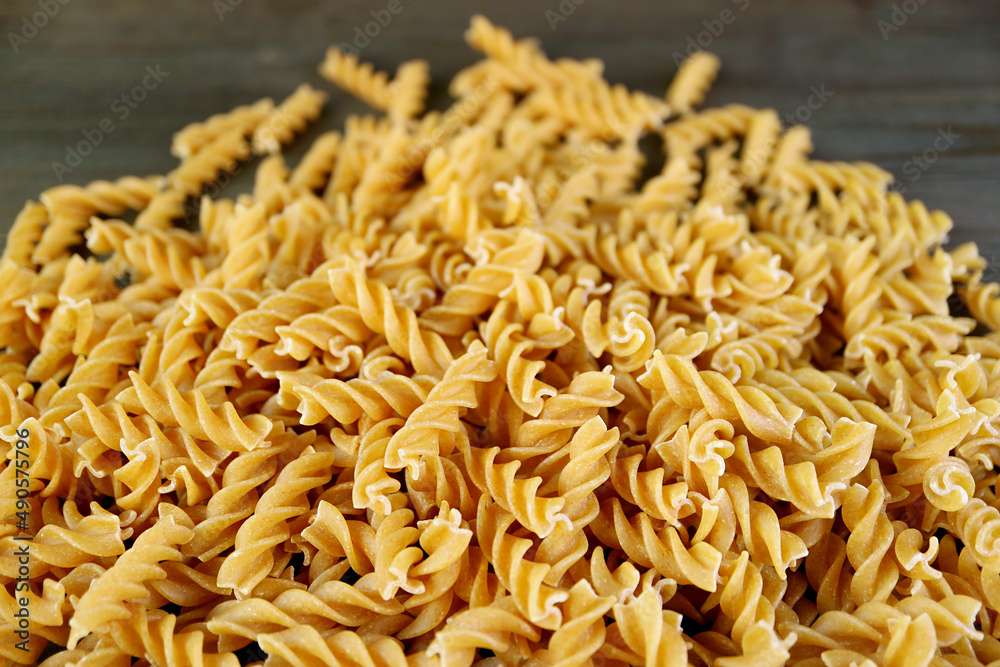 Pile of Uncooked Whole Wheat Fusilli Pasta for the Concept of Wellness Pile of Uncooked Whole Wheat Fusilli Pasta for the Concept of Wellness