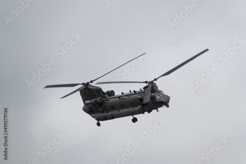 Fototapeta Naklejka Na Ścianę i Meble -  close up of an RAF Chinook tandem-rotor CH-47 helicopter flying fast and low in a cloudy blue grey sky on a military battle exercise, Wilts UK