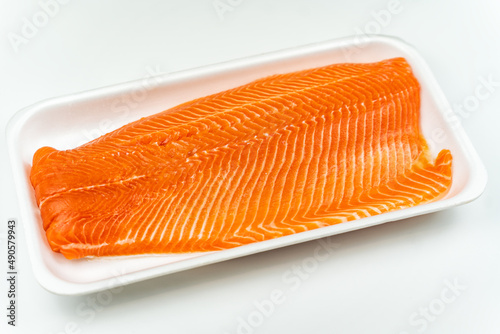 Raw salmon fillets on a white plastic plate on a white background.