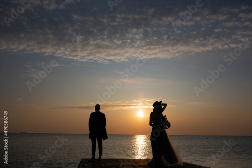 A couple standing on an empty sea beach at sunset. 